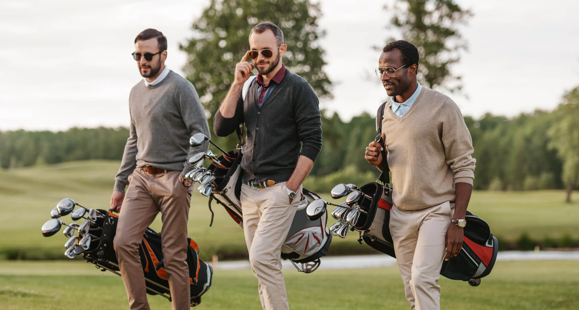 tri osobe igraju golf sa sunčanim naočalama i golf torbama