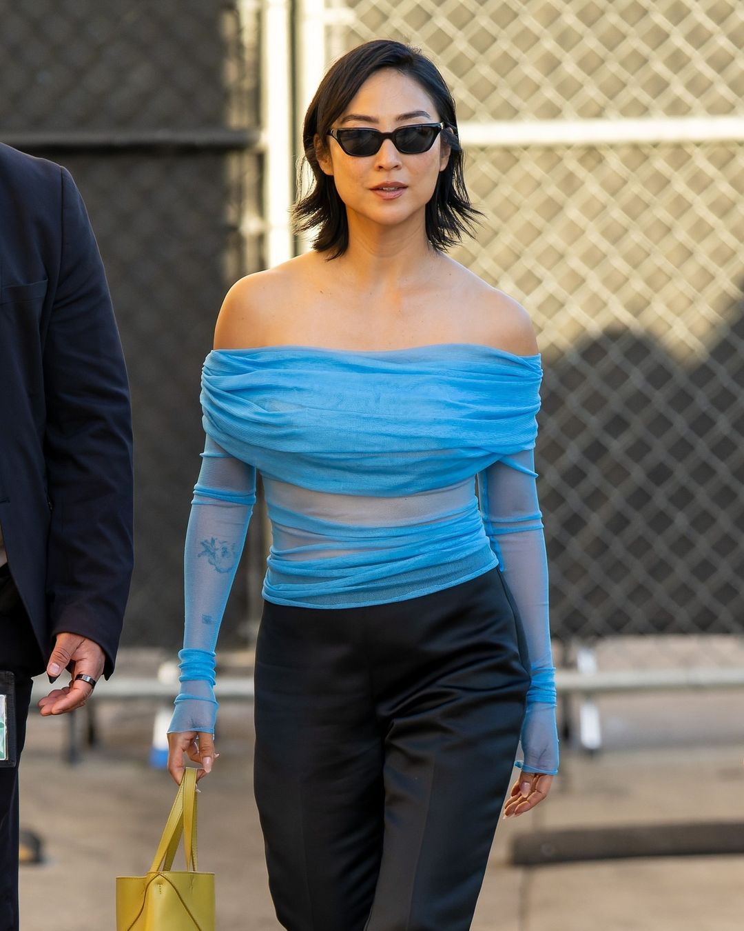 greta lee u plavom topu i crnim sunčanim naočalama vani