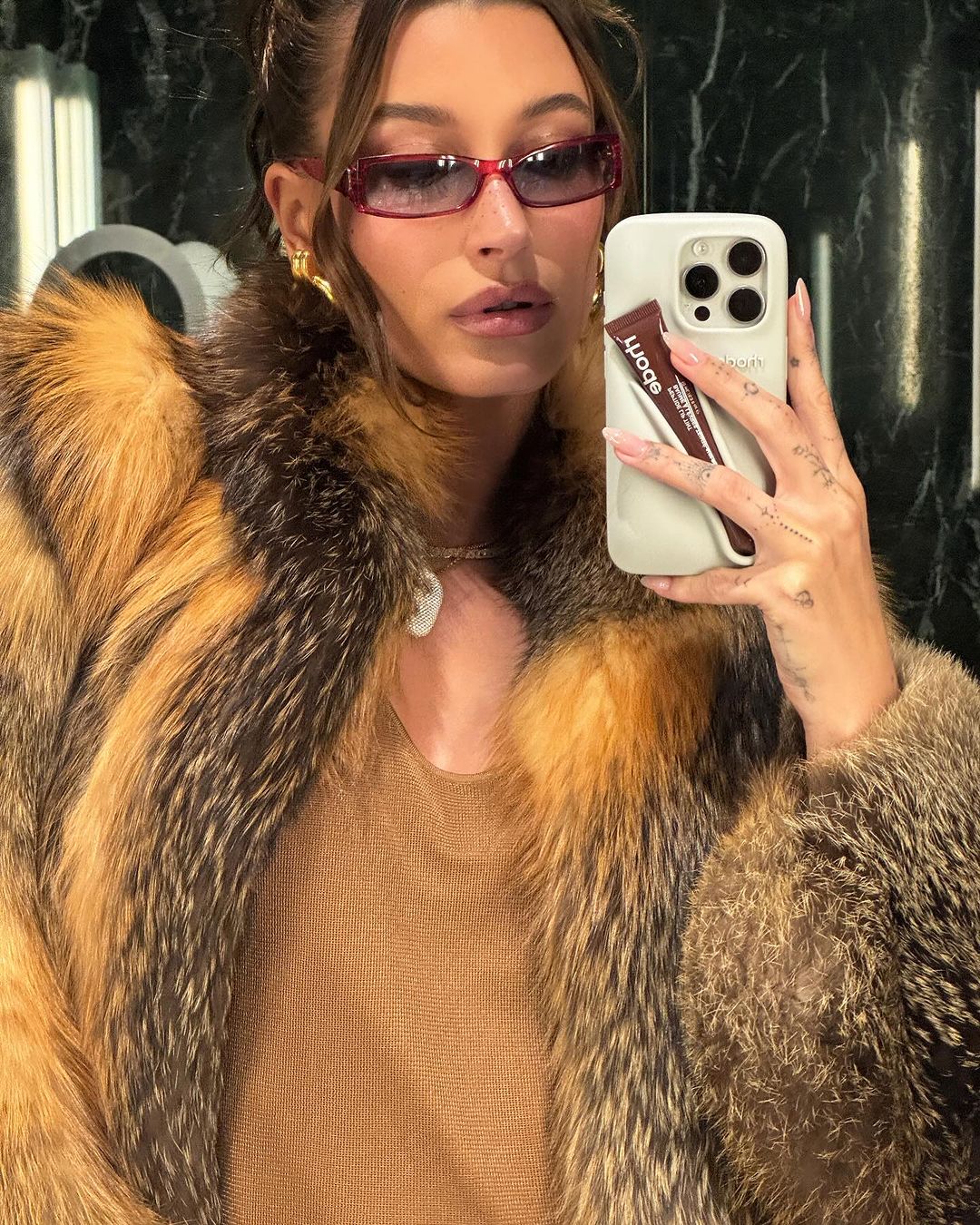 hailey bieber slika se u ogledalu dok nosi sunčane naočale